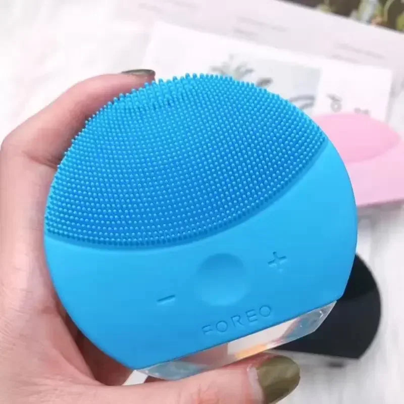 Sheluxe silicone facial cleansing brush for sensitive skin in blue held in hand with soft silicone bristles