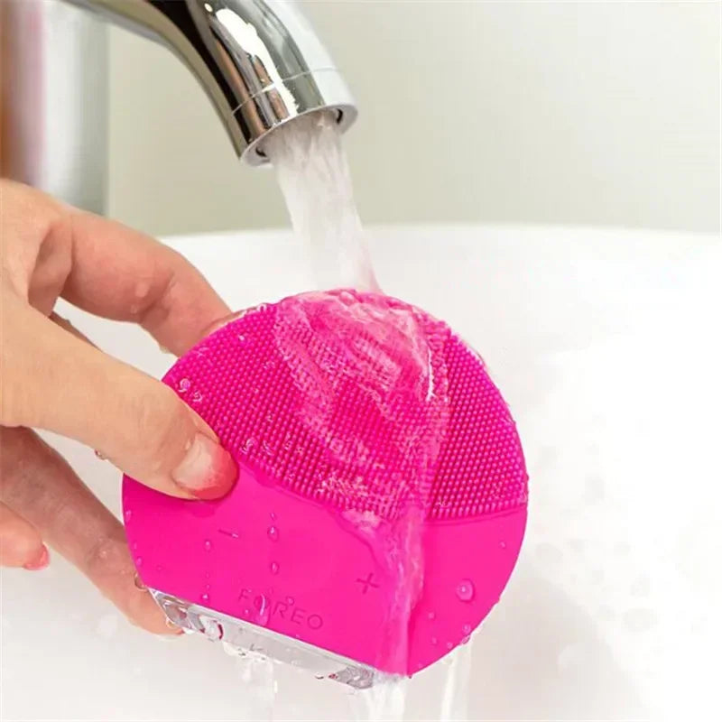 Sheluxe silicone facial cleansing brush for sensitive skin rinsed under running faucet water