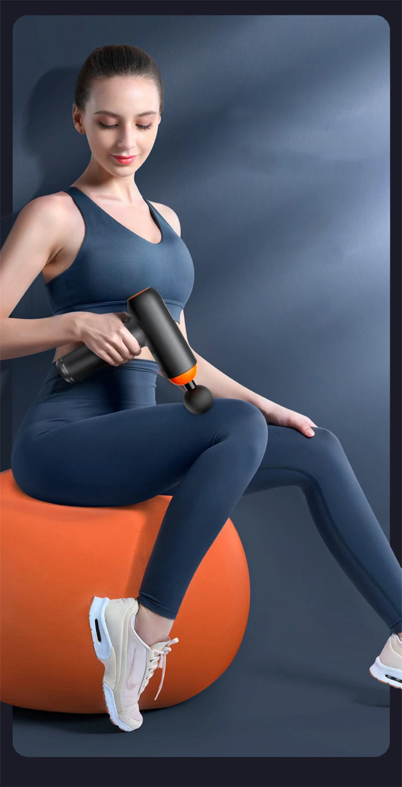 Woman using Sheluxe massage gun for back and leg pain relief on her thigh while sitting on an exercise ball